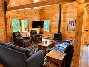 Ein gemütliches Blockhaus-Interieur mit Kamin, Ledermöbeln und einem Fernseher.