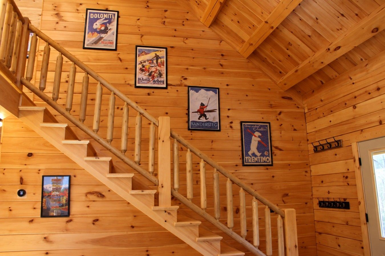 A wooden staircase with handrails, wooden walls, and framed posters.
