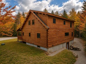 Eine Blockhütte mit Veranda, zahlreichen Fenstern und einer Schotterauffahrt.
