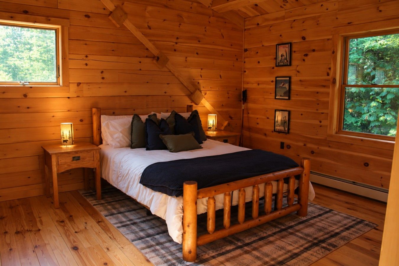 Ein Schlafzimmer einer Holzhütte mit einem Bett, Nachttischen und einem karierten Teppich.