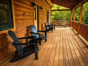 Una cabaña de madera con porche y sillas Adirondack.