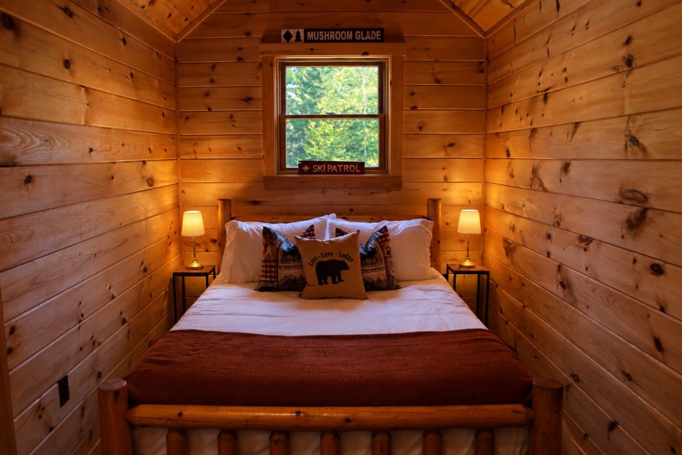 Une chambre confortable, aménagée dans un chalet en bois, avec un lit, des oreillers et une fenêtre.