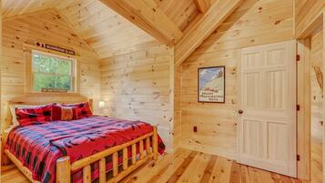 Een houten kamer met een bed, een raam, een deur en een poster aan de muur.