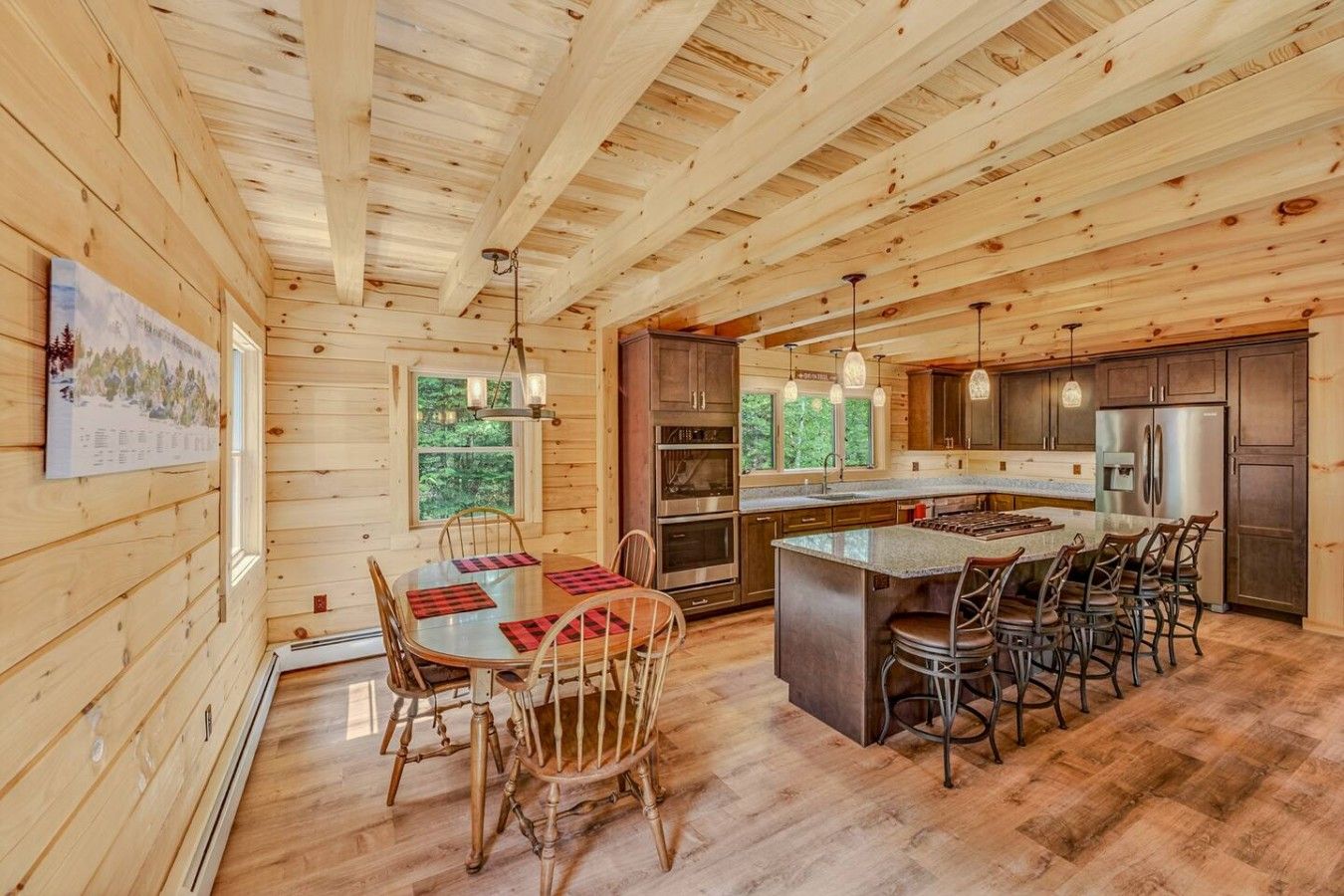 Een houten cabin met een eethoek, keuken en grote ramen.