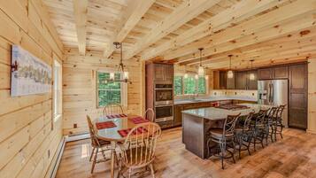 Een houten cabin met een eethoek, keuken en grote ramen.