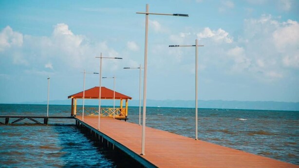 Une jetée s’avançant dans des eaux calmes, dotée d’un espace de repos abrité et de lampadaires.