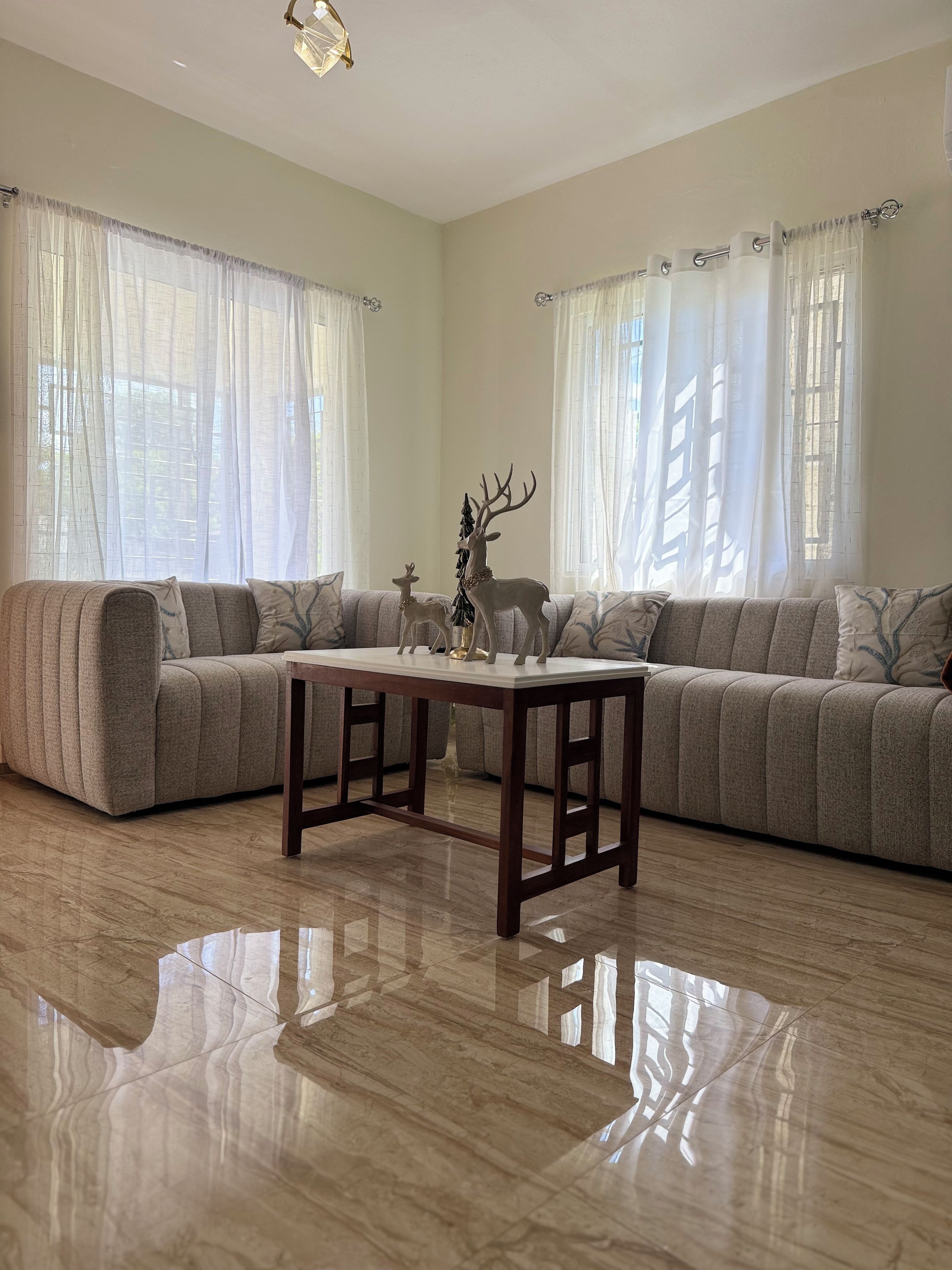 A living room with a sectional sofa, a wooden coffee table, and a decorative deer statue.