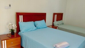 Une chambre d’hôtel avec un lit simple, une table de chevet, une petite table et une petite plante en pot.