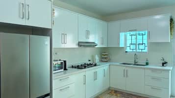 A modern kitchen with white cabinets, stainless steel appliances, and a window with a geometric pattern.