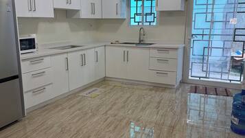Una cocina con gabinetes blancos, un refrigerador de acero inoxidable, un microondas y un fregadero.