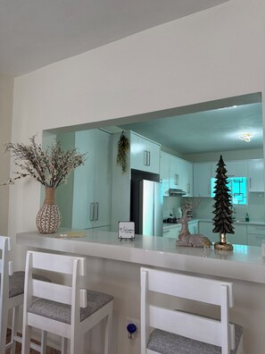 Eine moderne Küche mit weißen Schränken, einem Edelstahl-Kühlschrank und einem weihnachtlichen Schmuckbaum.