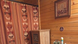 Ett badrum med träpanel, toalett, skåp, duschdraperi och en inramad tavla på väggen.