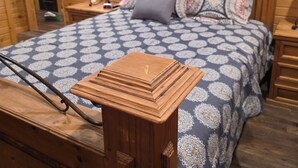Ett rum med träpanel, en säng, två sängbord, en lampa och en dekorativ väggdekoration.