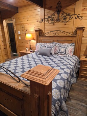A wooden room with a bed, nightstands, a lamp, and a decorative wall piece. - Cozy 2bdrm, 1 bath cabin right in the middle of the Bitterroot Valley. (Victor)