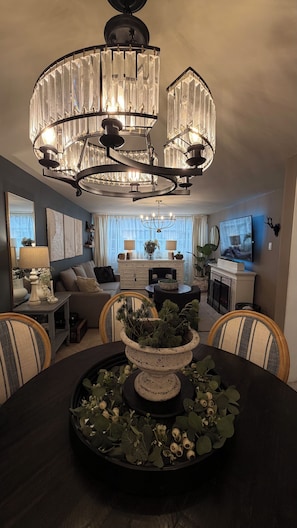 A modern living room with a chandelier, a fireplace, a television, and a dining area with a table and chairs. - Beautiful, Cozy, and Quiet Apartment in Coyoacán, Mexico City (Ciudad de México)