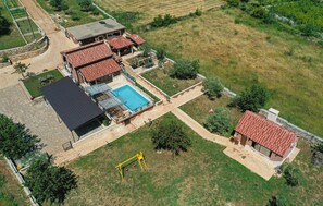 An aerial view of a residential property with a swimming pool, multiple buildings, and a swing set. - Amazing home in Divojevici with private swimming pool, can be inside or outside (Divojevici)