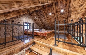 An attic bedroom with a stone wall, wooden beams, a bed, and a metal railing. - Amazing home in Divojevici with private swimming pool, can be inside or outside (Divojevici)