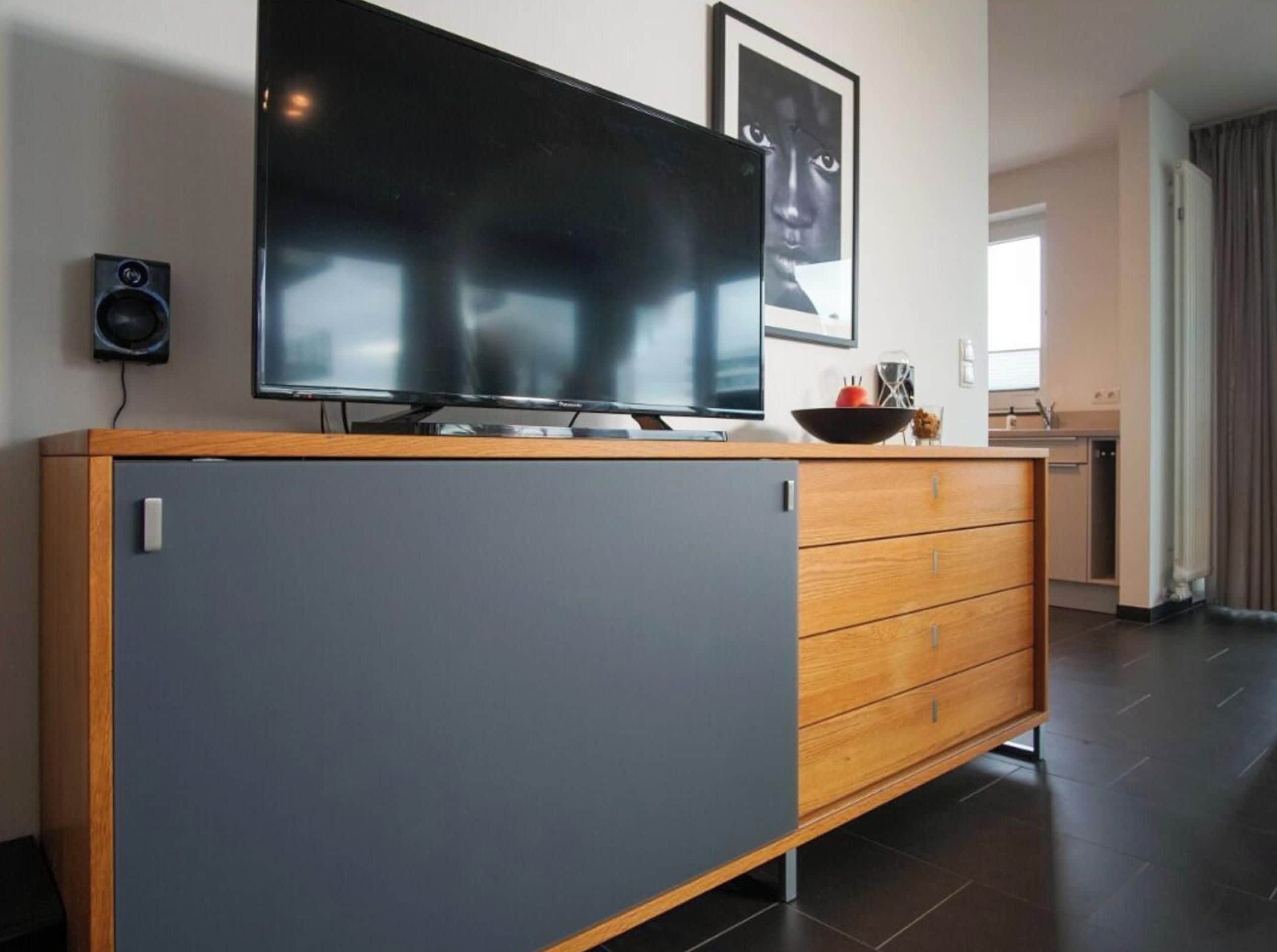 Una cocina moderna con un televisor de pantalla plana grande montado sobre un mueble de madera con cajones.
