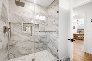 Un bagno moderno con box doccia in vetro, pareti in marmo e un pavimento a pattern esagonale.