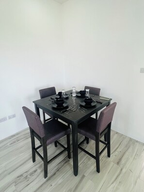 Une table à manger avec quatre chaises, de la vaisselle noire et un téléphone intelligent posé sur la table.