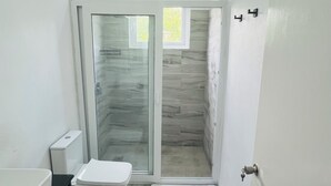 Ein modernes Badezimmer mit einer gläsernen Duschkabine, Toilette und Waschbecken.