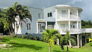 Ein zweistöckiges Gebäude mit Balkon, umgeben von Gras und Palmen.