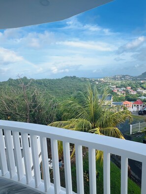 A balcony with a white railing overlooking a lush green landscape with a view of a town in the distance. - Modern Diamond View Apartments 2 - Close to Rodney Bay and Airport (Gros Islet)