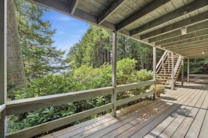 A wooden deck with a railing, surrounded by dense greenery and trees. - Center Harbor Lake Escape | Private Dock (Center Harbor)