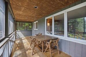 A wooden deck with a table and chairs, overlooking a forested area. - Center Harbor Lake Escape | Private Dock (Center Harbor)