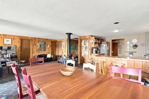 A cozy, wood-paneled room with a large dining table, chairs, a fireplace, and a kitchen area. - Center Harbor Lake Escape | Private Dock (Center Harbor)