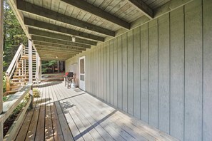 Um deck de madeira coberto com uma escadaria que leva a uma porta, cercado por um muro de madeira.