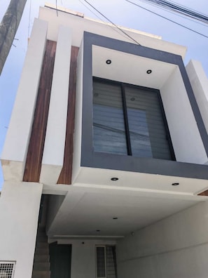A modern building with a flat roof, a large window, and a visible door.