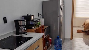 Cuina compacta amb fogó integrat, nevera i cafetera.