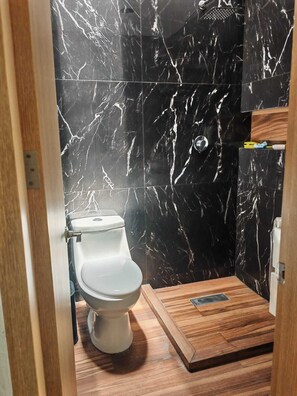 Ein Badezimmer mit Toilette, Dusche und Holzboden.