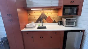 Een kleine keuken met een magnetron, broodrooster en spoelbak.