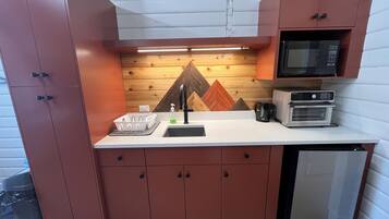 A compact kitchen with a microwave, toaster, and sink.