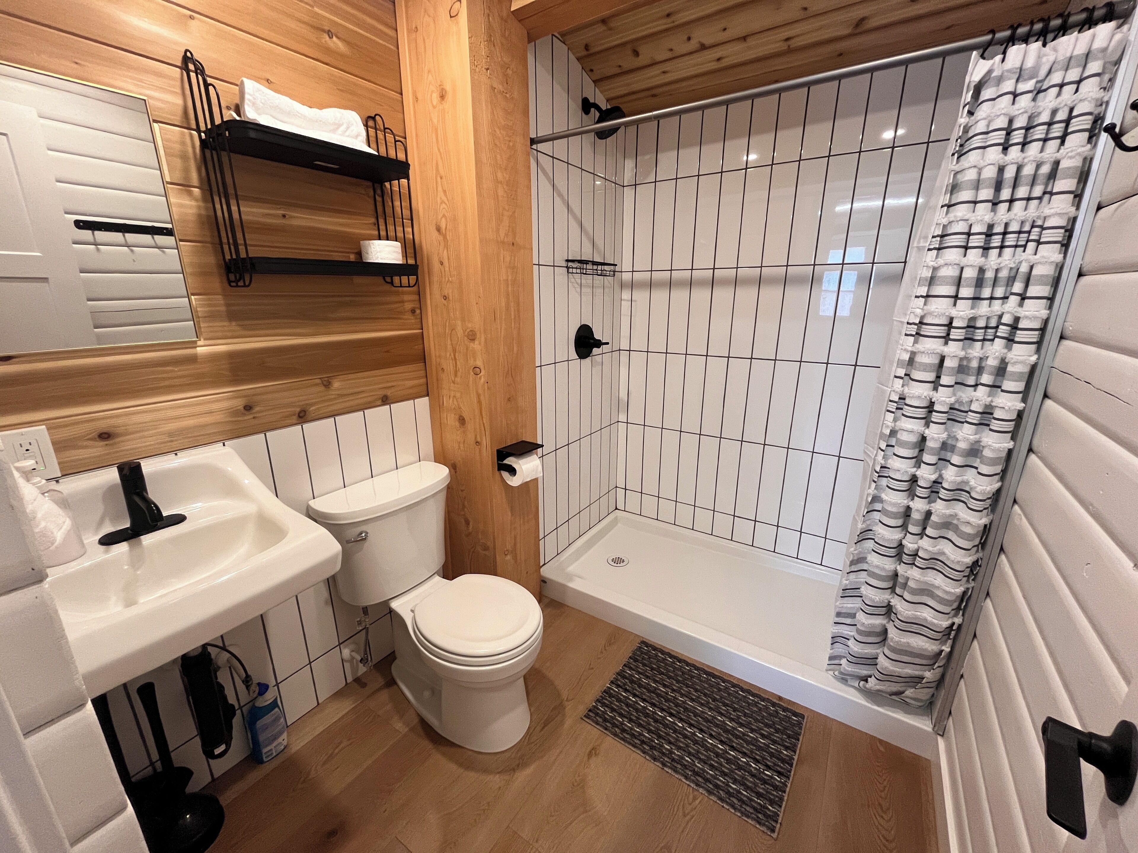 Un baño con tocador de madera, inodoro, cabina de ducha y bañera.