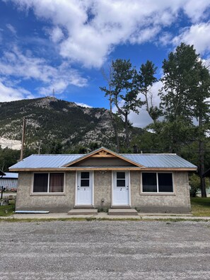 Petit edifici amb teulada metàl·lica, dues portes i finestres. Està situat en una zona rural amb una muntanya al fons.