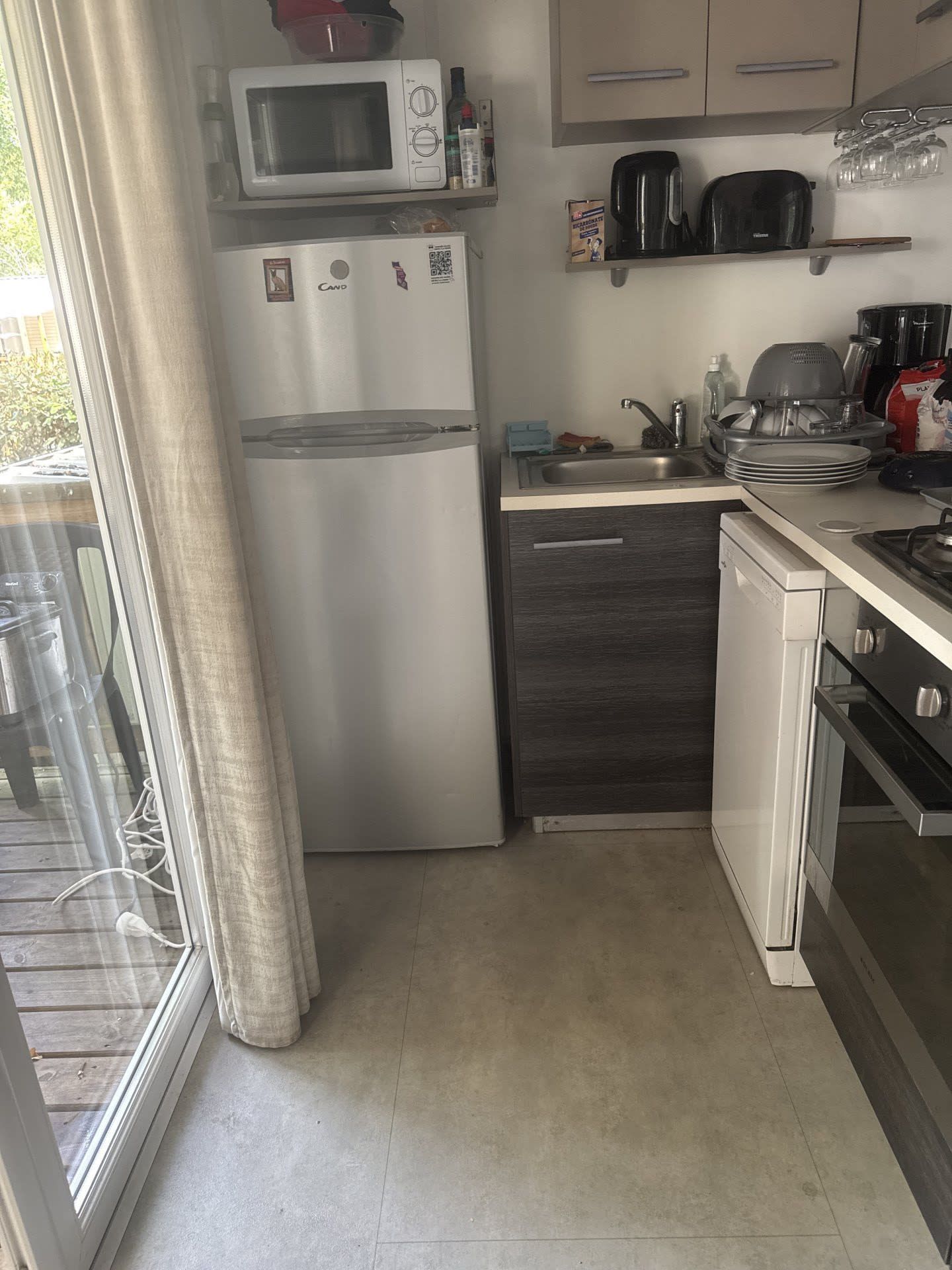 Una cocina funcional con refrigerador, microondas, lavaplatos y estufa.