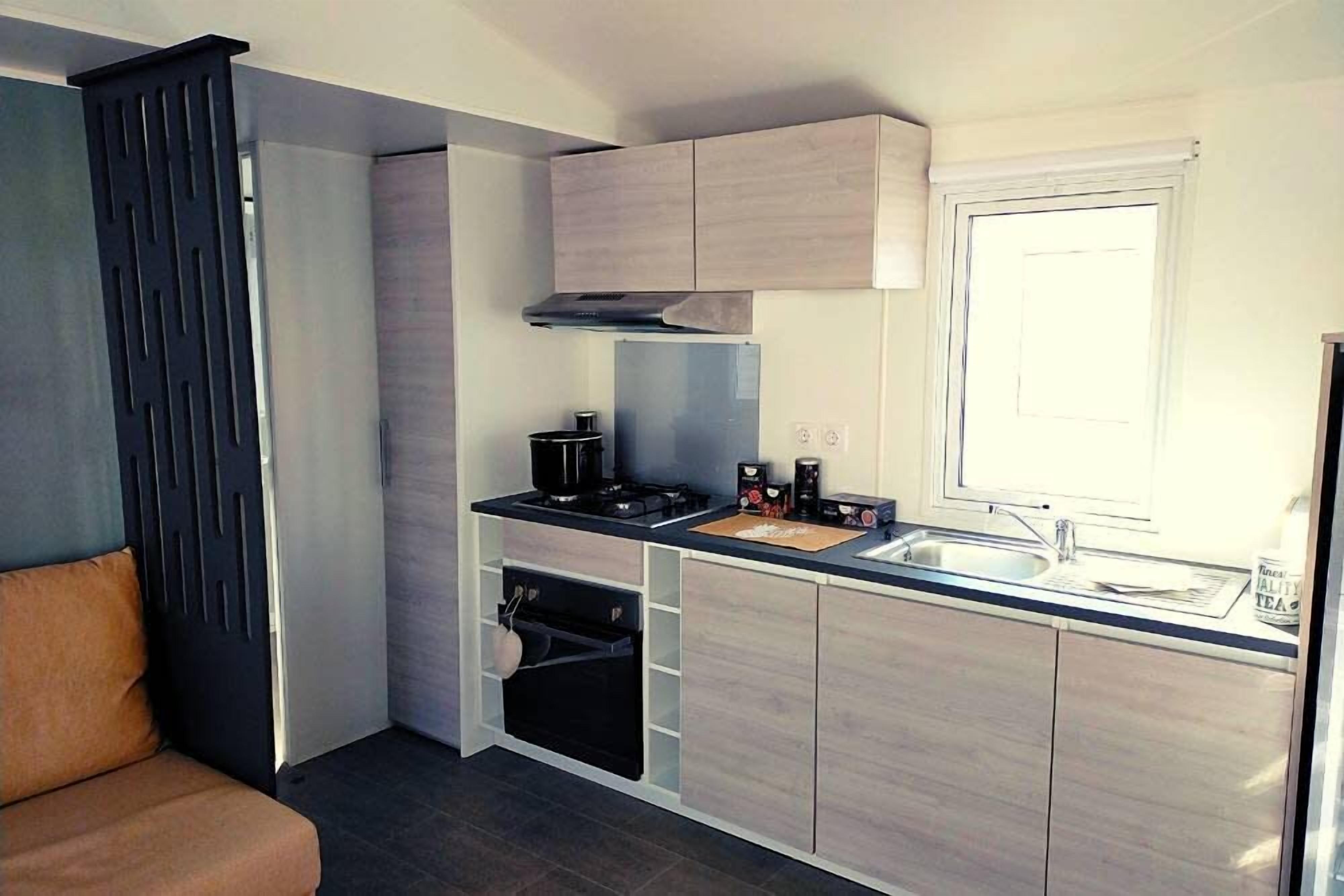 A compact kitchen with a built-in oven, a stovetop, and a window.
