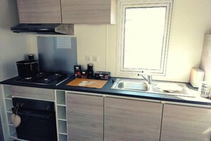 A modern kitchen with a gas stove, a built-in oven, a stainless steel sink, and a window above the sink. - Mobilhome 2 chambres 2 SDB (Canet-en-Roussillon)