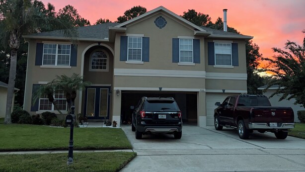 Une maison à deux étages avec un garage, une allée et un VUS garé.