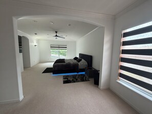 Een slaapkamer met een bed, een nachtkastje, een bureau, een plafondventilator en een raam met zonwering.