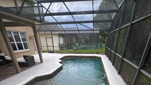 Un espace piscine doté d’une structure en verre, d’un jacuzzi et d’une terrasse avec des sièges.