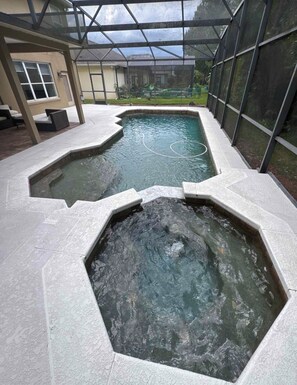 Een zwembadgedeelte met een glazen omheining, een jacuzzi en een terras met zitplaatsen.