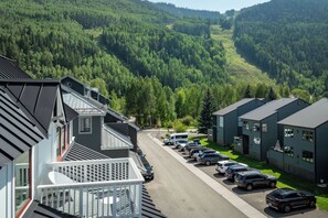 Ein Wohngebiet mit modernen Häusern, einem Parkplatz und einem bewaldeten Tal im Hintergrund.