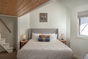 A bedroom with a bed, two bedside tables, a window, a staircase, and a framed picture on the wall. - Downtown Telluride Condo | Walk to Gondola | Mountain Views | Sleeps 6 (Telluride)