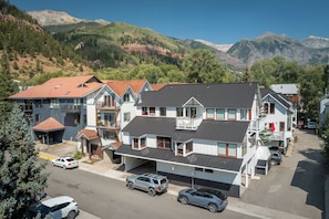 Ein mehrstöckiges Wohngebäude mit Garage, überdachtem Stellplatz und Blick auf Berge im Hintergrund.