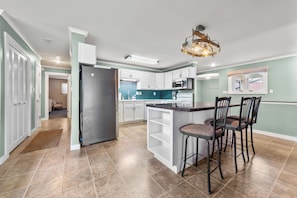 A modern kitchen with a central island, white cabinetry, and a stainless steel refrigerator. - Loonar Landing: (Cheboygan)  Lakefront on Long Lake, Sleeps 8 (Cheboygan)
