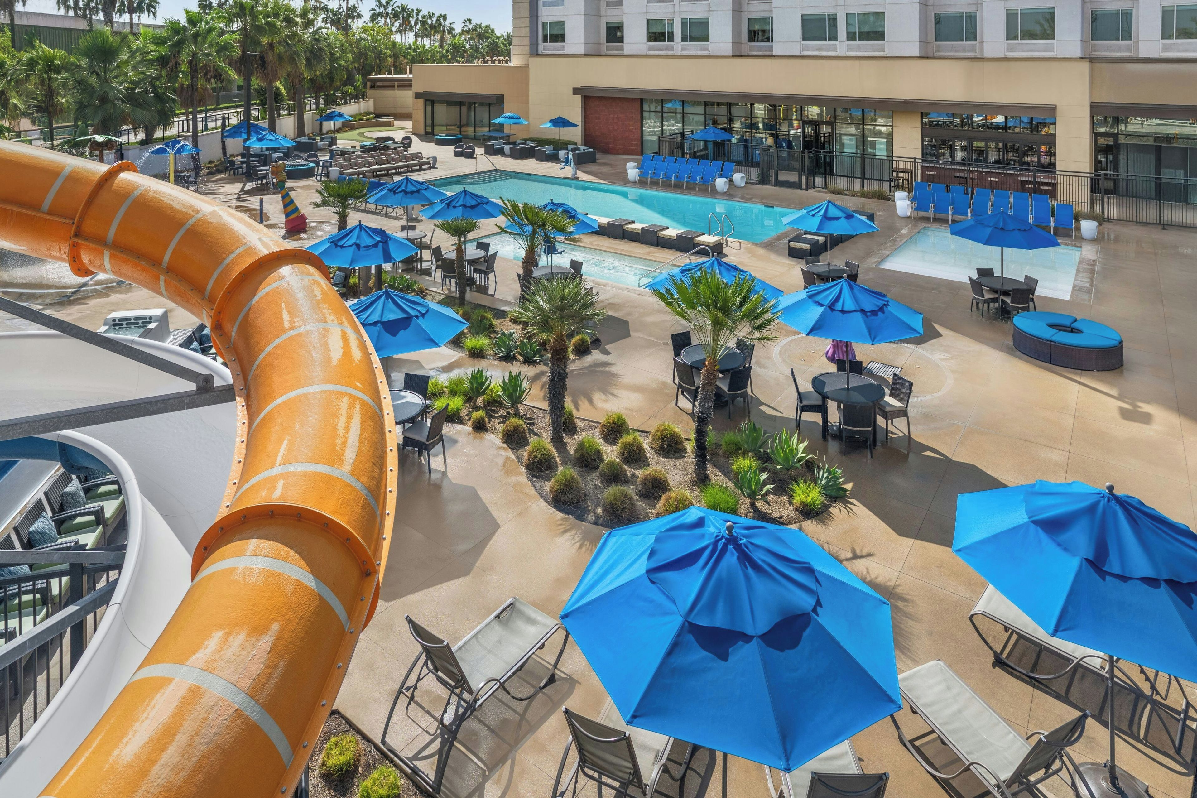 Área de piscina no terraço com várias piscinas, espreguiçadeiras e guarda-sóis.